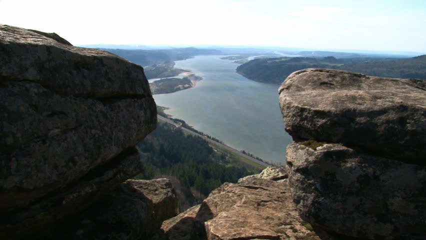 Person hiking and leaping across rocks atop cliff in Oregon up the Gorge.