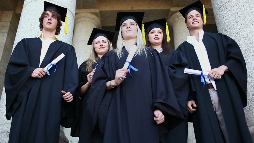 Happy graduated students raising their arms in front of the university