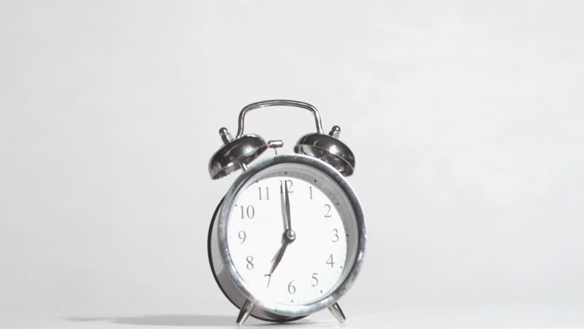 Alarm clock sounds in a super slow motion crushing by a hammer against a white background