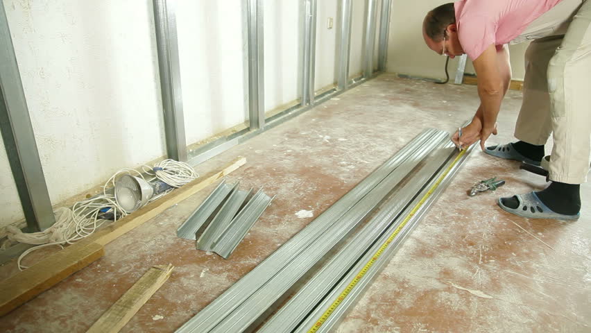 Man installing plasterboard walls in the house, metering a size of drywall studs