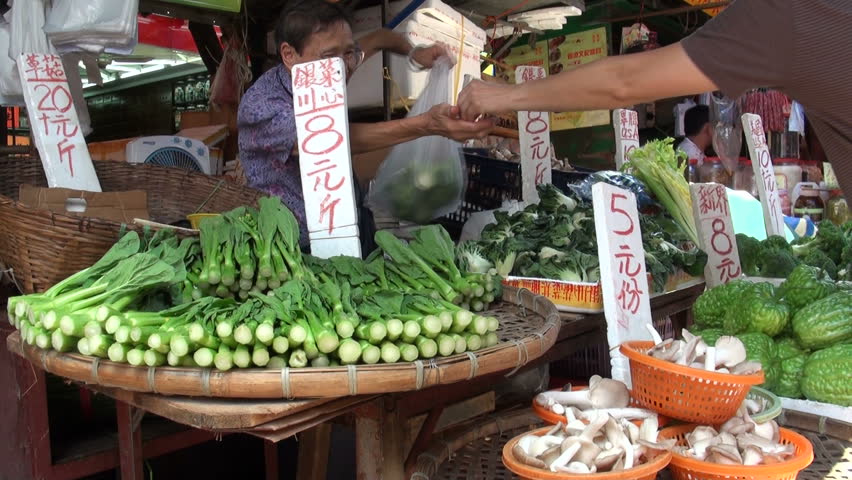 HONG KONG - 28 JULY 2010: An elderly lady is selling fresh vegetables and fruit at a local market in Kowloon, Hong Kong