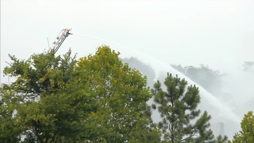 Smoke From Large Outdoor Fire Rising Around Working Ladder Mounted Remote Control Cannon