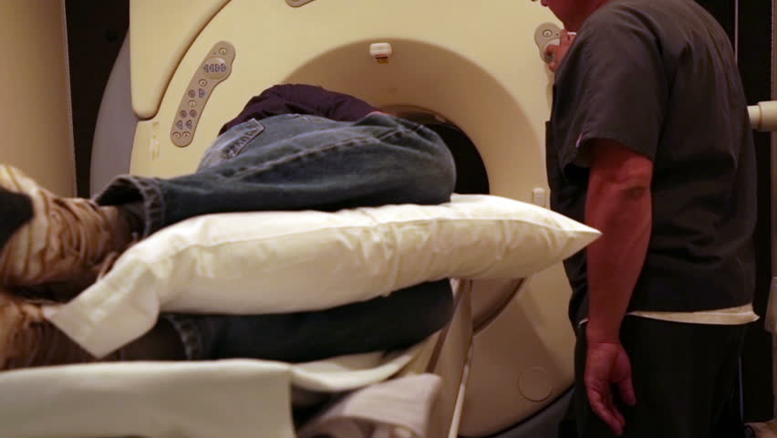Emergency hospital portable MRI on patient. Man lays in Magnetic Resonance Image device to look deep into soft muscles and bones. Injury diagnostic before surgery. Doctor radiologist clinical exam.