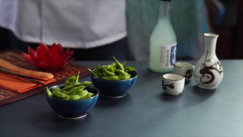 Lock down shot of chef sprinkling salt on Edamame (soy beans) with sake included.