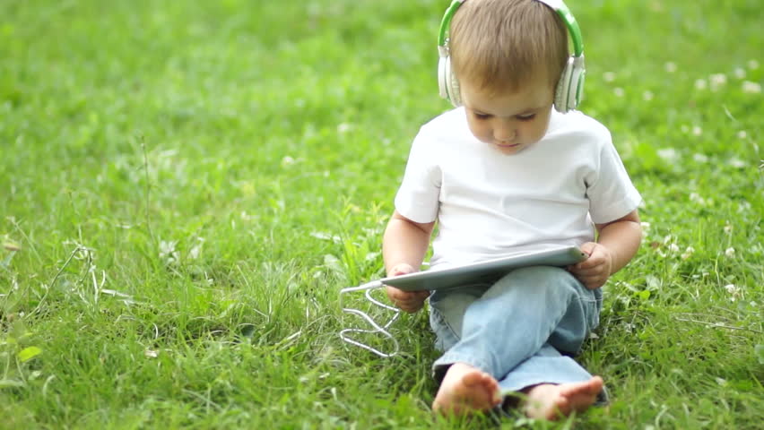 Boy with a tablet PC in headphones outdoors
