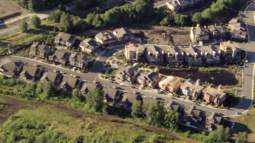 Aerial view from low-flying airplane of new suburban neighborhood street and houses under construction