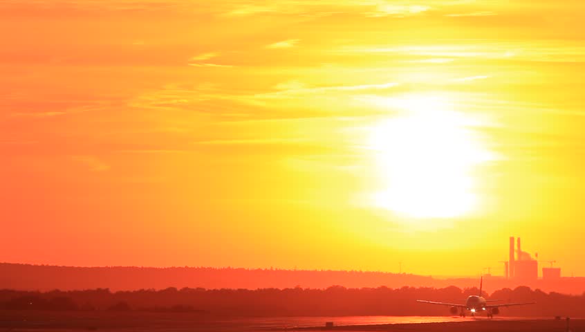 Passenger jet plane taking off runway in sunset