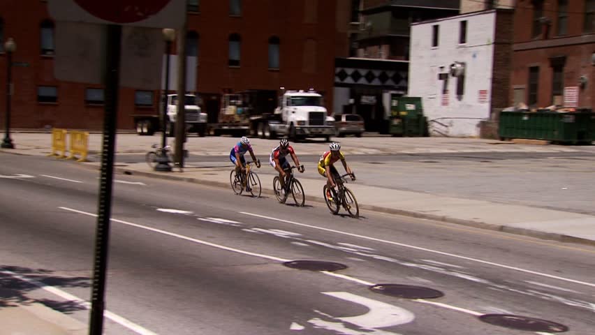 PROVIDENCE, RHODE ISLAND - SEPTEMBER 3, 2009: Three men rounding street corner in bicycle race in city - slow motion