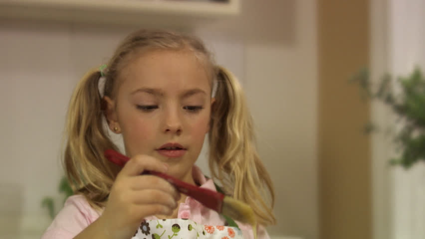 Girl brushing cinnamon bun with beaten egg