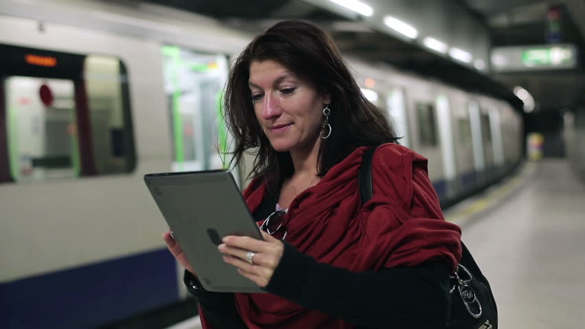 Young woman using tablet computer on subway station
