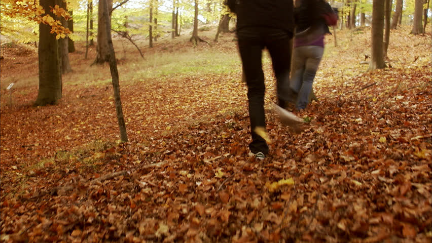 A couple running and playing in a forest during autumn