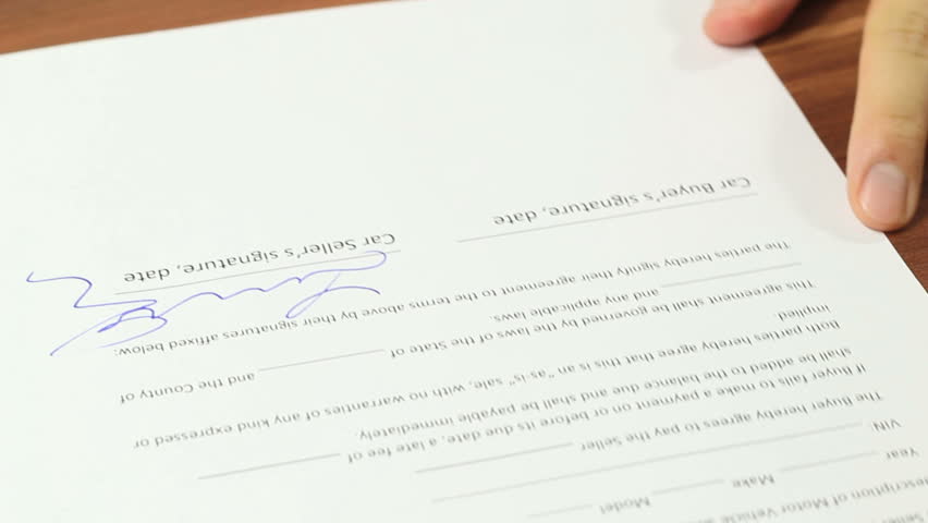 Man buying a car and signing car sale contract on the car buyers signature line
