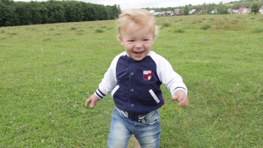 The one year old cute fair-head boy is making his first steps