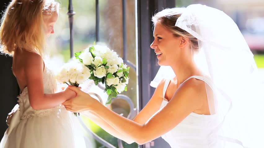 Beautiful young bride hugging cute little bridesmaid before wedding