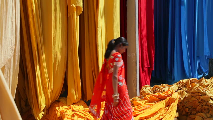 Rajasthan, India - CIRCA May 2011: Woman in Saree checking the quality of freshly dyed fabric hanging from Bamboo poles to dry, Sari garment factory