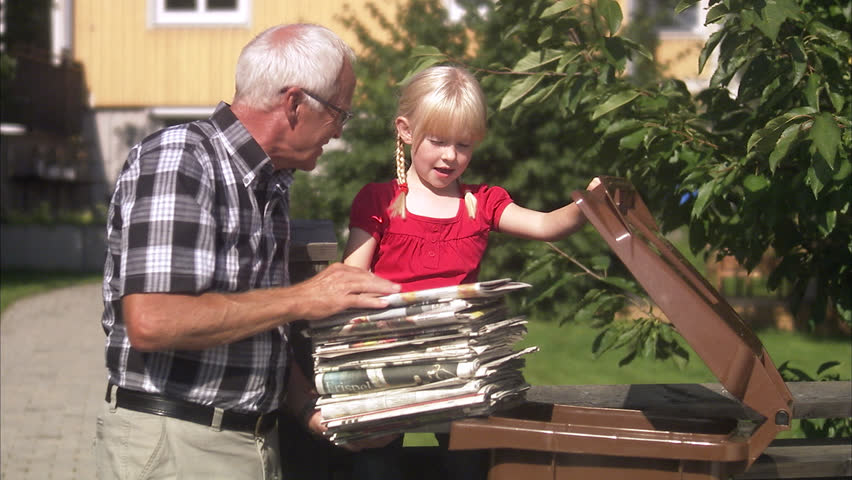 Girl and senior man recycling newspapers