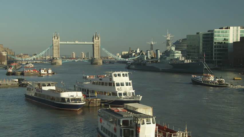 LONDON - CIRCA 2011: Pool of London with Tower Bridge, City Hall, HMS Belfast and More London Place in the background, moored boats in the foreground a tug tows refuse waste barges downstream circa 2011 in London, England.