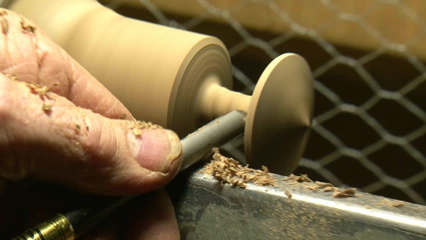 man working on wood lathe creating a wooden âspinning topâ using a skew chisel

