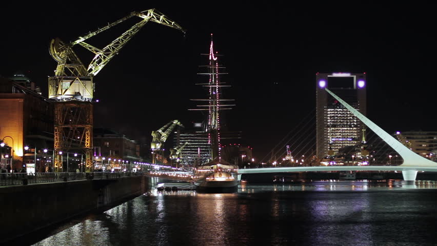 Night view of elegant Puerto Madero harbor, Buenos Aires, with the landmark Puente de la Mujer footbridge, a museum ship and a boardwalk with decorative cranes (Sep 2011).