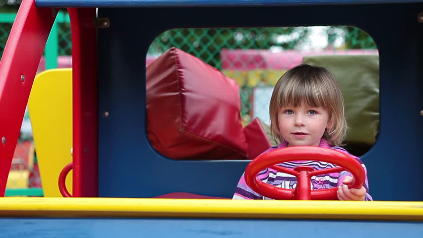 Small Caucasian playful child playing in car with steering wheel