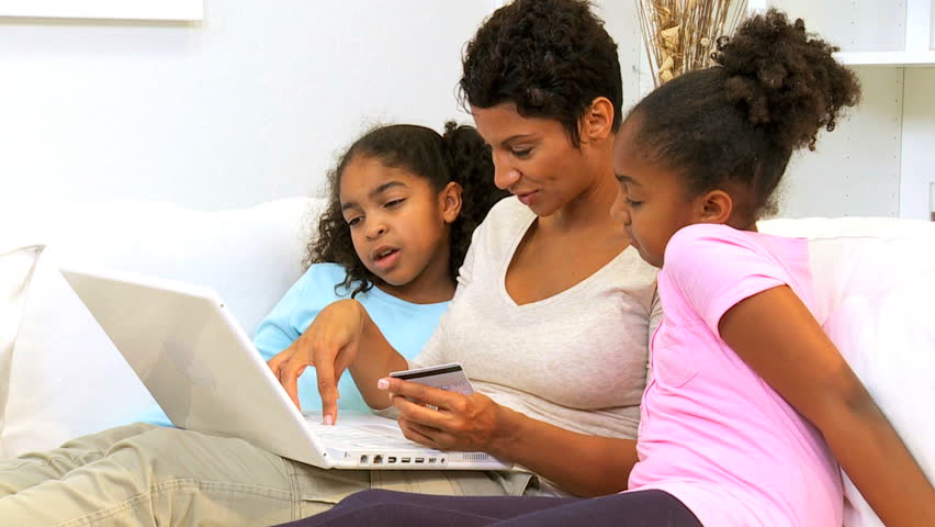 African American mother and daughters browse content on the internet, laptop