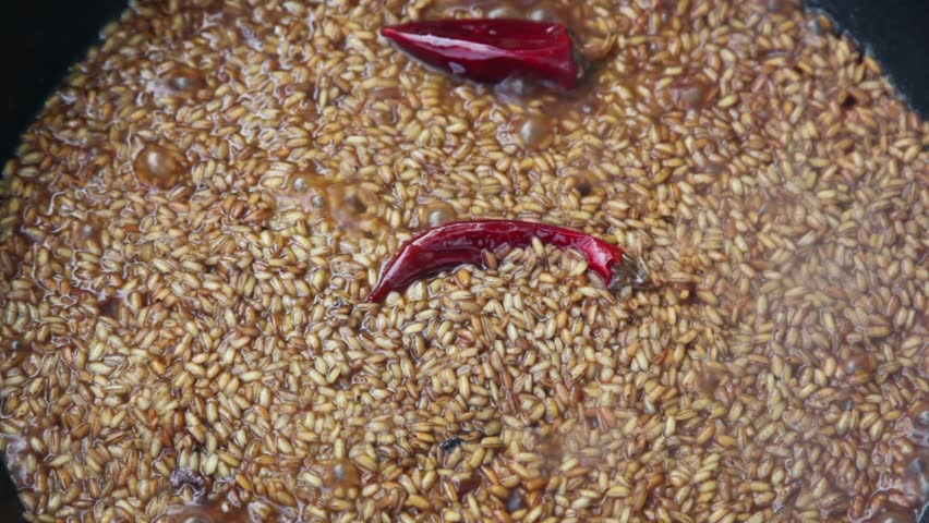 Red pepper in broiled rice boils at pot on campfire