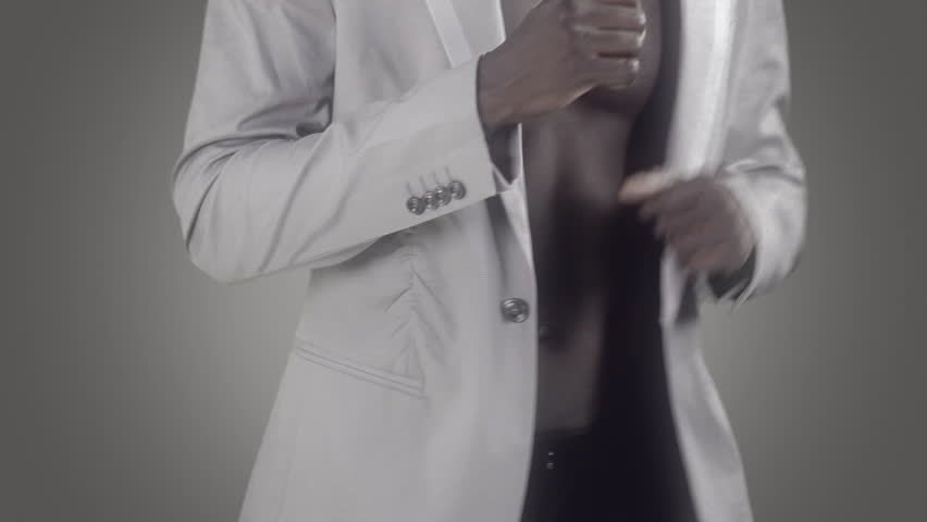 young african guy waving and dancing with a cool attitude, pointing to the camera with an elegant suite