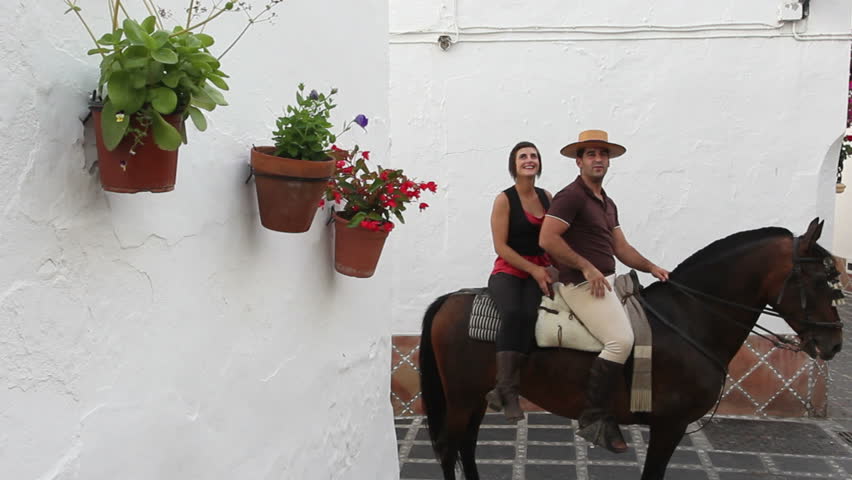 Man and woman on horseback exploring a village in Andalusia, Spain