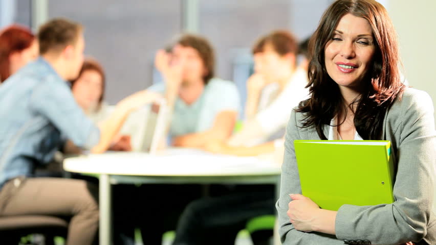 Portrait of young Caucasian brunette tutor learning college young classmates in modern campus classroom