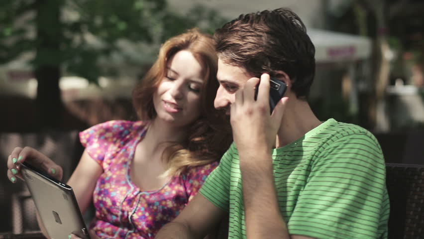Young couple with tablet computer and cellphone, steadicam shot
