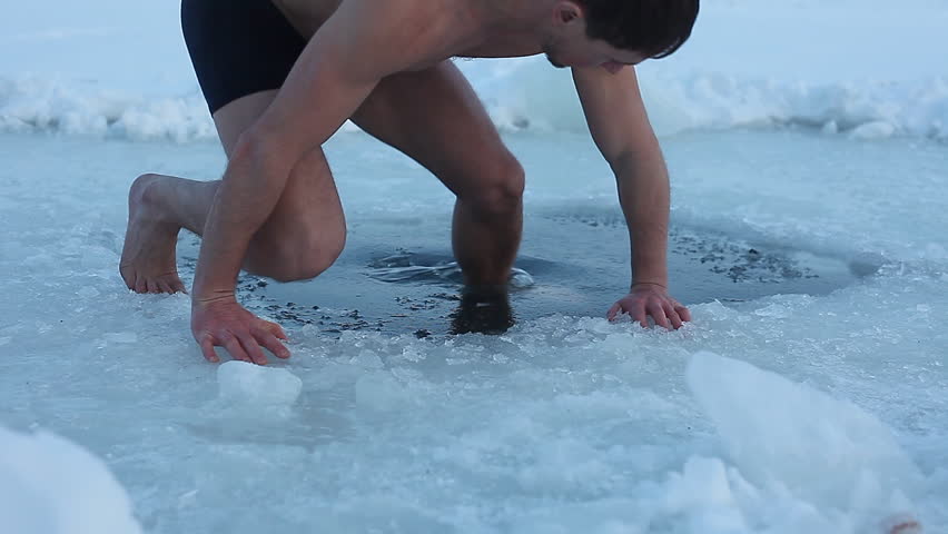 Young man having recreation swim in an ice hole