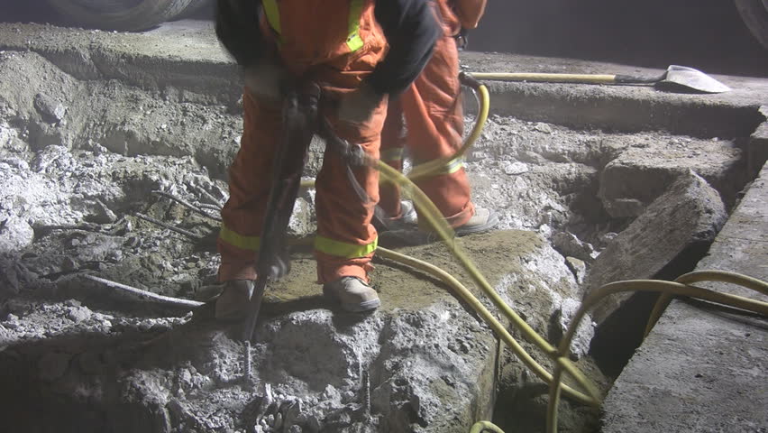 Jackhammers. Good audio. Wide shot. Road crew working at night under bright lights.