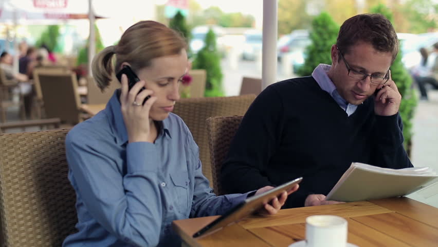 Businesspeople talking on cellphones in the restaurant, outdoor


