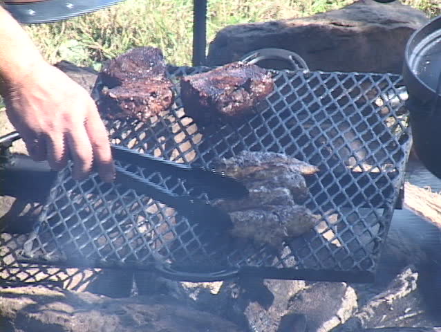 Chicken and steak being removed from open-fire grill