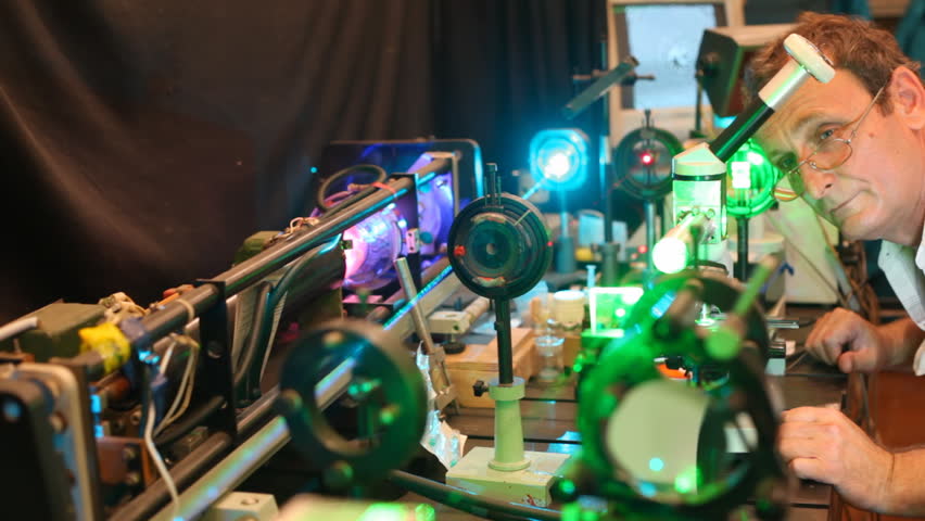 system of electronic devices with lasers and magnifying glasses and scientist who is adjusting them