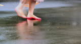 Indian hindu female with red dye (aalta-sign of hindu married woman) on her foot walking in slow motion on wet surface after rain