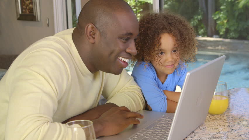 African American father and daughter using laptop