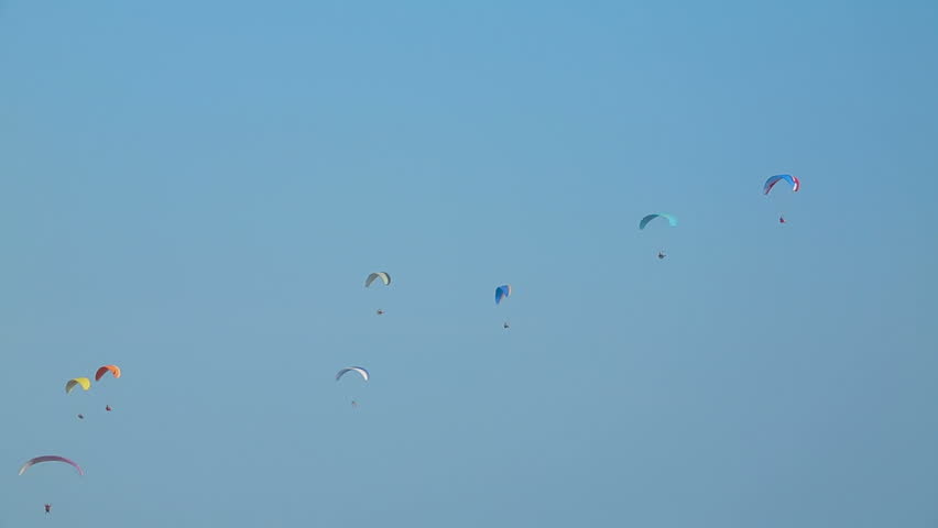 Numerous paragliders flying in the sky on a sunny day.
Gliding on a sunny day.