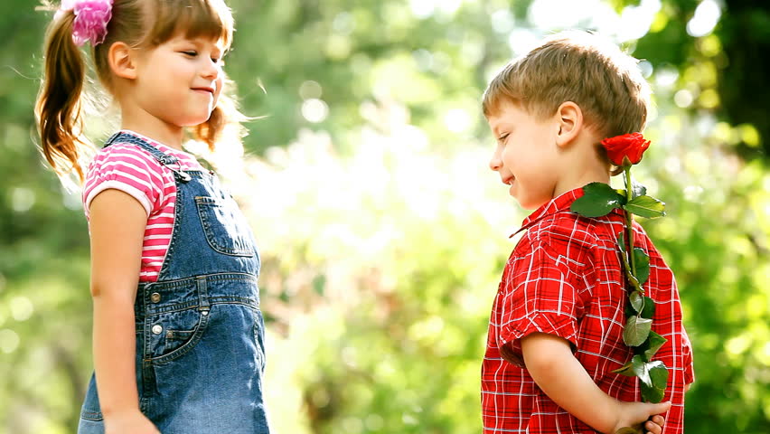 Two children speaking and boy present flower