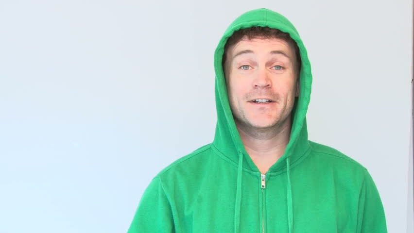 Happy man dressed in green drinks from mug with green liquid.