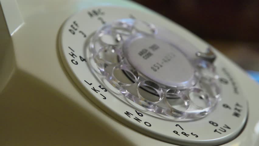 Closeup shallow depth of field shot of someone dialing an old rotary style telephone.
