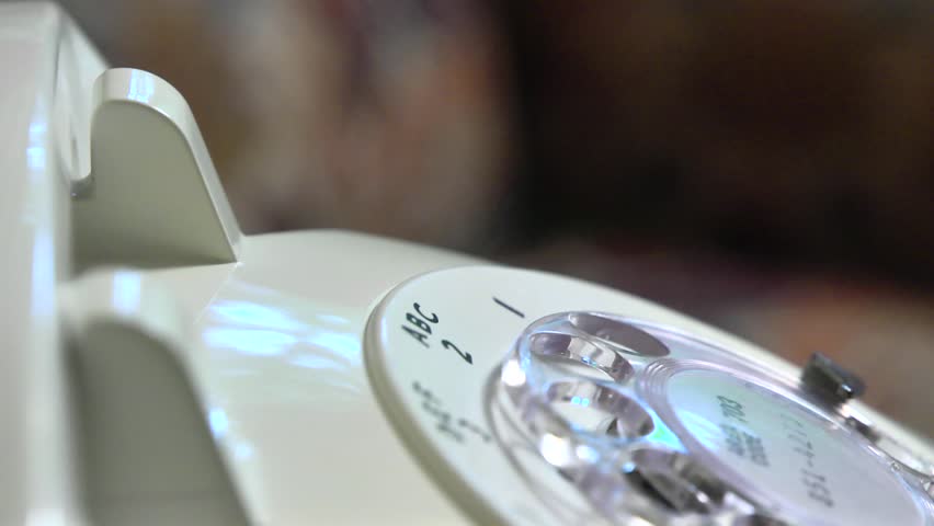 Closeup shallow depth of field shot of someone dialing an old rotary style telephone.