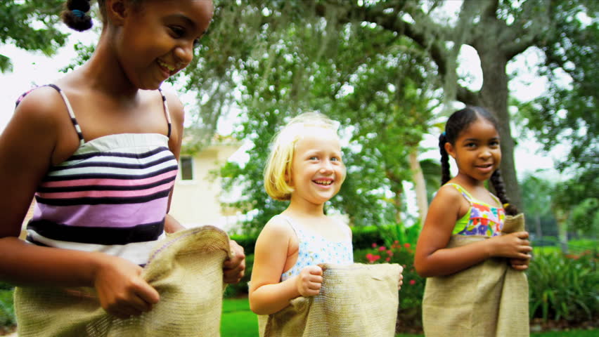 Little African American Caucasian girls taking part in fun sports events in home garden shot on RED EPIC