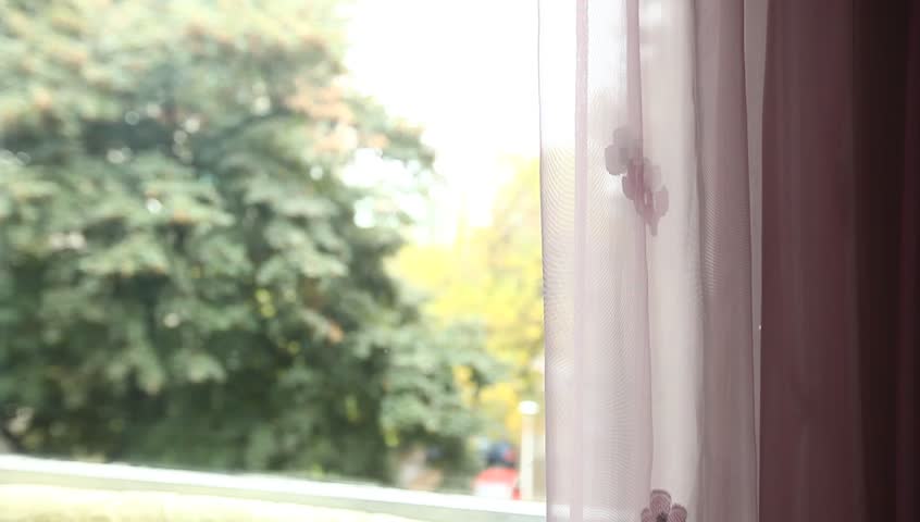 Young adult woman comes to window, finger draws and speaks.
