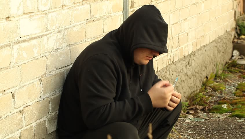 Drug addict man leaning against the wall