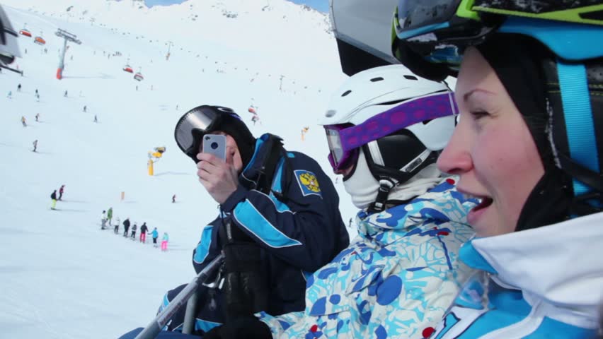One of three skiers makes photo by cellphone during ropeway ride at mountains