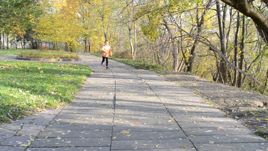 Little girl runs on a footpath in autumn park