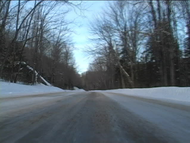 Low angle view of a car driving through remote area with roads filled with snow