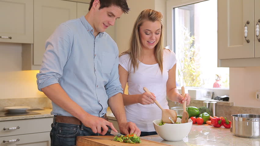 Couple preparing salad together in kitchen