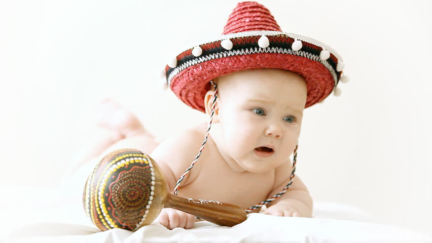 Baby in sombrero hat with maracas on the light background